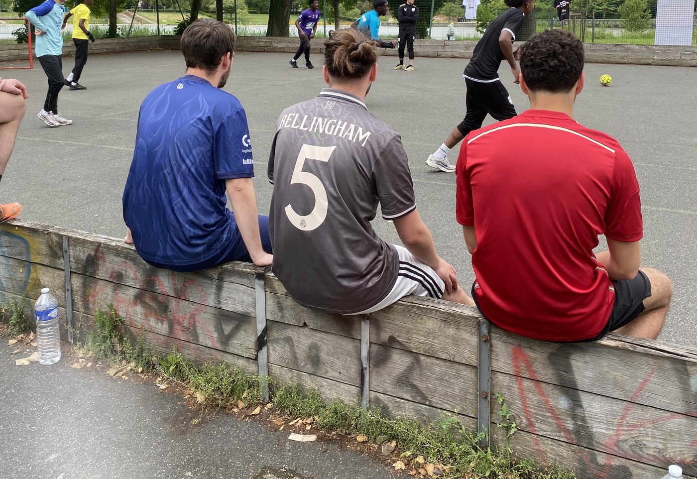Joueurs assis sur une bordure, regardant un match sur un city stade à Amiens