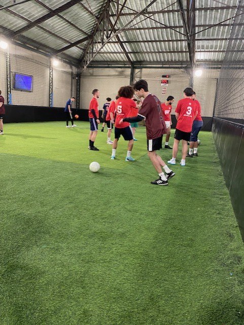Match de foot à 5 en salle à Lille, joueurs en maillots rouges.